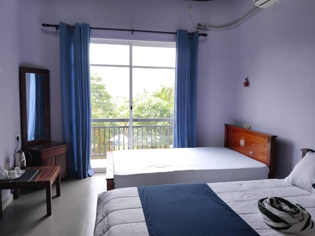 Un dormitorio con cama, escritorio, espejo y ventana con cortinas.