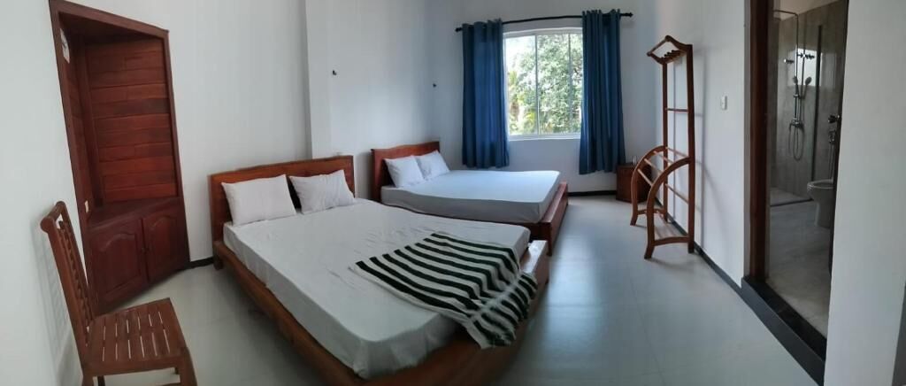 Een slaapkamer met twee bedden, een houten stoel, een houten kast en een raam met gordijnen.