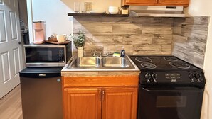 A kitchen with wooden cabinets, a microwave, a sink, and a stove. - Cozy studio in beautiful Flagstaff with cool AC for your stay (Flagstaff)