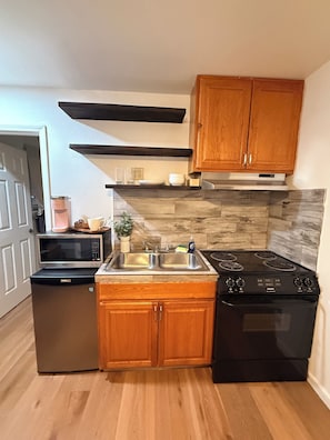 A kitchen with wooden cabinets, a microwave, a sink, and a stove. - Cozy studio in beautiful Flagstaff with cool AC for your stay (Flagstaff)