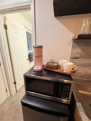 A kitchen with a Cuisinart microwave, a Keurig coffee maker, and a wooden tray with cups and a plate. - Cozy studio in beautiful Flagstaff with cool AC for your stay (Flagstaff)