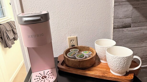 A Keurig coffee maker on a black countertop with a wooden tray holding a mug and a container of coffee pods. - Cozy studio in beautiful Flagstaff with cool AC for your stay (Flagstaff)