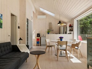 Ein modernes Interieur mit einer Couch, einem Esstisch, Stühlen und einer Küchenzeile.