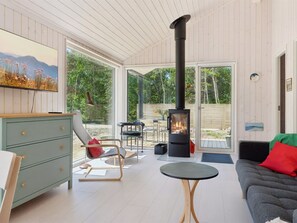 Ein modernes Wohnzimmer mit Kamin, einer Couch, einem Essbereich und Blick ins Freie.