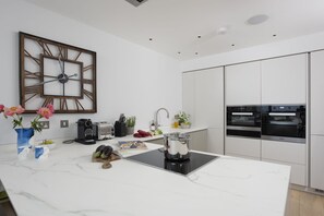 Eine moderne Küche mit Marmorarbeitsplatte, integriertem Backofen und einer dekorativen Uhr an der Wand.