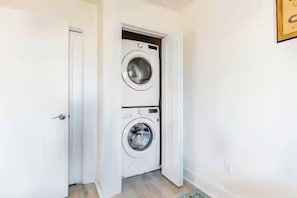 A laundry room with two stacked washing machines and a door leading to another room. - Bayview Bliss at Bridge Point 225 (Ocean City)