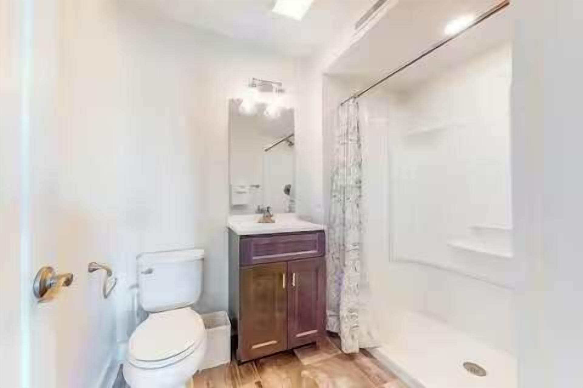Un baño con inodoro, lavamanos, armario y ducha.