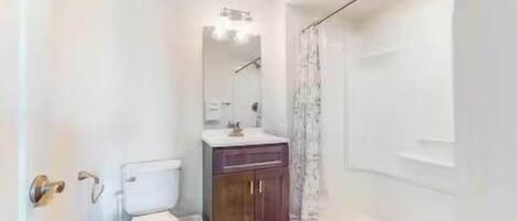 Un baño con inodoro, lavamanos, armario y ducha.