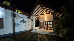 Una casa con porche cubierto, un mural de delfines y un sendero de ladrillos.