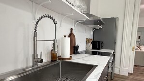 Una cocina moderna con un lavamanos de acero inoxidable, un microondas y un botellero.