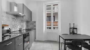 Una cocina moderna con horno empotrado, estufa y microondas. Hay una mesa de comedor con sillas y una ventana con vistas al exterior.