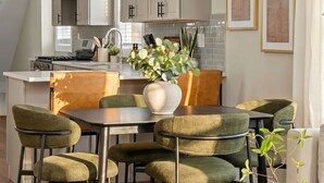 A modern kitchen with a dining area, featuring a central island, pendant lights, and a view of the living room. - Spacious 7BD/7BR Home in Somerville, 10 mins to Boston, Harvard, MIT (Somerville)