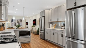 A modern kitchen with stainless steel appliances, grey cabinets, and a central island. - Spacious 7BD/7BR Home in Somerville, 10 mins to Boston, Harvard, MIT (Somerville)