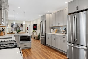 A modern kitchen with stainless steel appliances, grey cabinets, and a central island. - Spacious 7BD/7BR Home in Somerville, 10 mins to Boston, Harvard, MIT (Somerville)