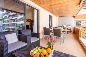 Ein Balkon mit Korbmöbeln, einem Essbereich und Blick auf ein Gebäude.