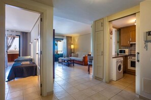 Ein Hotelzimmer mit einem Bett, einer Couch, einem kleinen Tisch und einer Küchenzeile inklusive Waschmaschine.