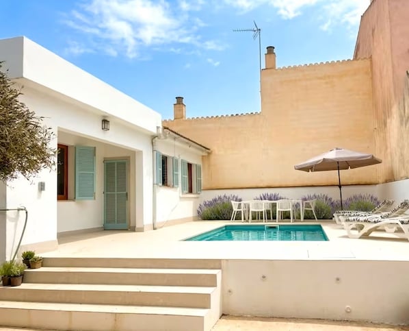 A modern house with a swimming pool, outdoor seating, and a staircase leading to the entrance.