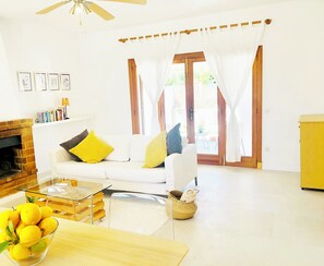 A living room with a white sofa, a glass coffee table, a brick fireplace, and a yellow cabinet.