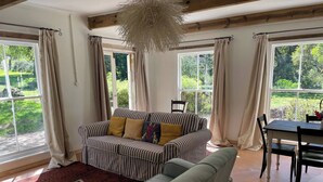 A living room with a striped sofa, a green sofa, a dining table, and a dog.