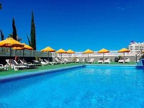 Ein Swimmingpool mit Sonnenschirmen, Liegestühlen und einem Gebäude im Hintergrund, das ein Casinoschild zeigt.