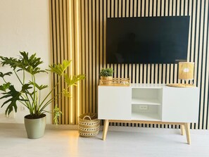 Ein modernes Wohnzimmer mit einer weißen Unterhaltungseinheit, einem Flachbildfernseher und Zierpflanzen.