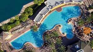 Vista aérea de um hotel com uma piscina grande e sinuosa, rodeada por espreguiçadeiras e palmeiras.