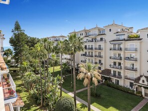 Ein mehrstöckiges Hotel mit Balkonen, einem gepflegten Rasen und Palmen.