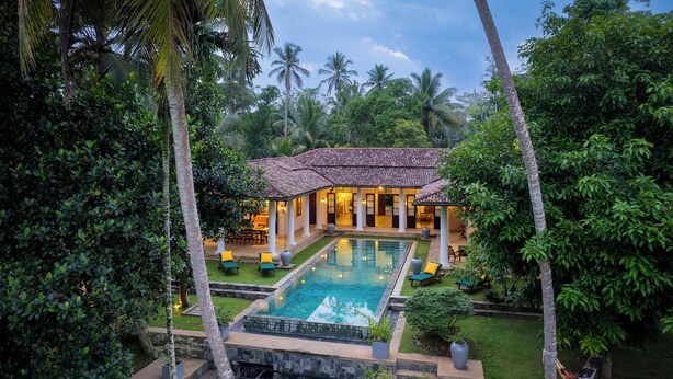A resort with a swimming pool, palm trees, and a well-maintained garden.