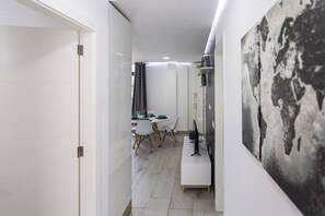 A narrow hallway leading to a dining area with a table set for two, a chair, and a computer on a desk. - Luxury Summerland: Stylish 1BR Retreat in Los Cristianos with Pool & Terrace (Los Cristianos)