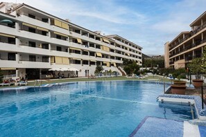 A hotel with a swimming pool, multiple balconies, and outdoor seating areas. - Luxury Summerland: Stylish 1BR Retreat in Los Cristianos with Pool & Terrace (Los Cristianos)