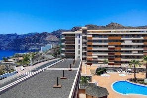Ein Hotel mit Pool, einer Straße und Bergen im Hintergrund.