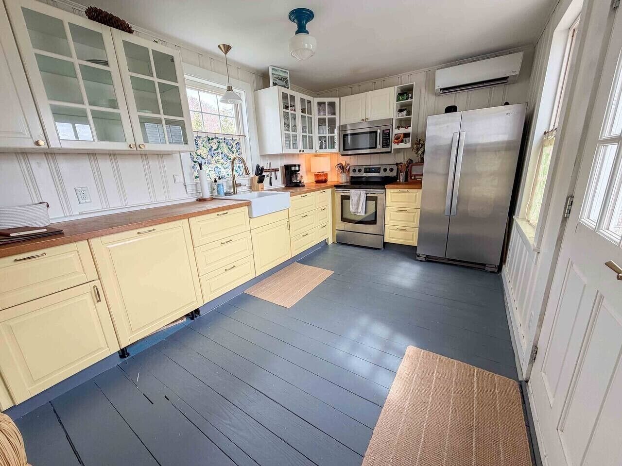 A kitchen with white cabinets, a stainless steel refrigerator, a microwave, and a stove.
