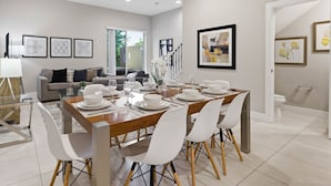 A modern dining area with a wooden table set for four, surrounded by white chairs. - Family Retreat With 4bed Suites Private Jacuzzi (Kissimmee)