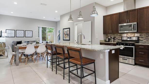 A modern kitchen with a central island, bar stools, stainless steel appliances, and pendant lighting. - Family Retreat With 4bed Suites Private Jacuzzi (Kissimmee)