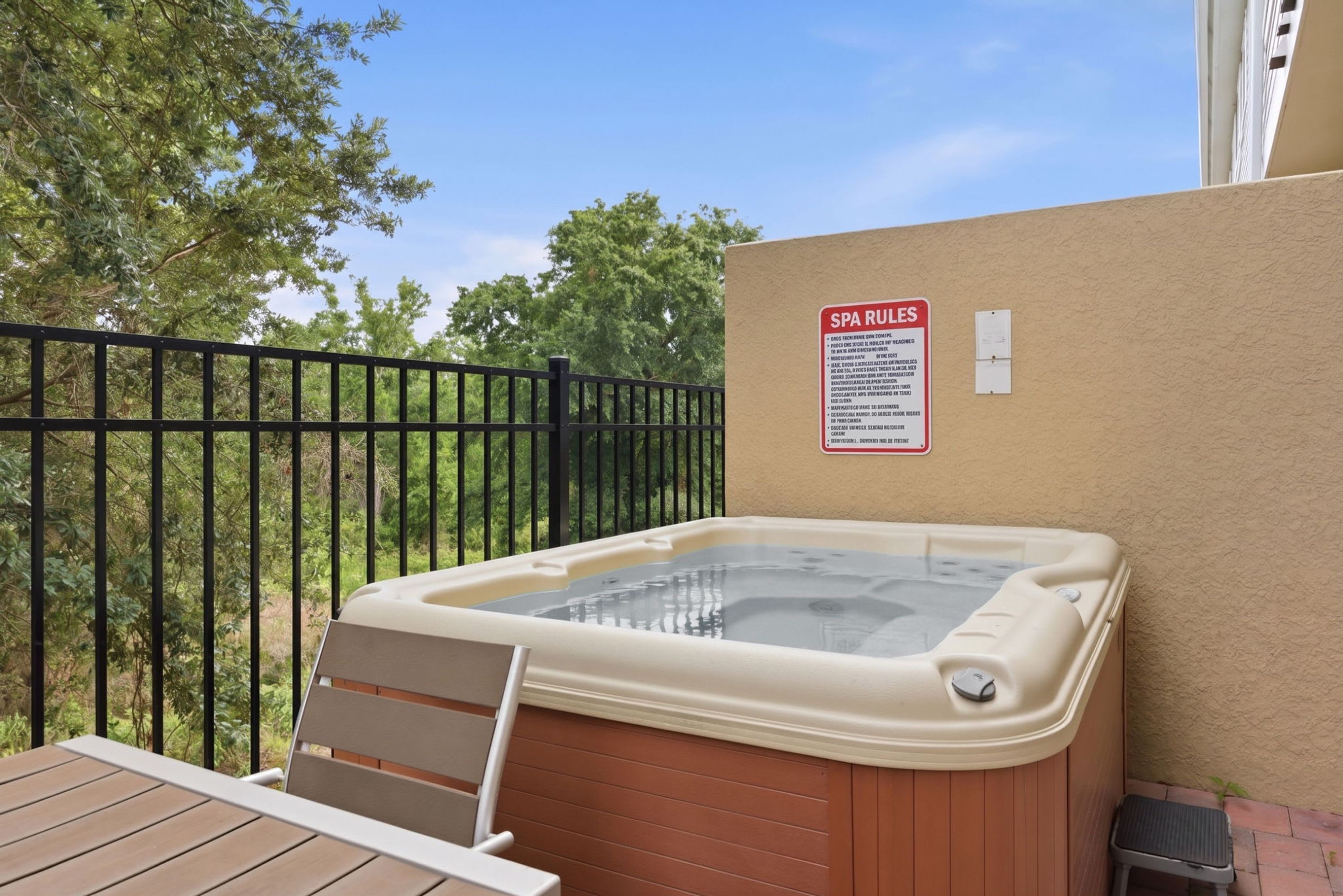 Un bain à remous doté d’une terrasse en bois et d’un panneau indiquant les règles à respecter dans le spa.