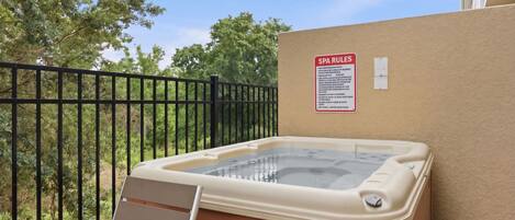 Un bain à remous doté d’une terrasse en bois et d’un panneau indiquant les règles à respecter dans le spa.