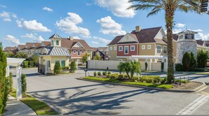 A residential street with houses, a gated entrance, and a clear sky. - Family Retreat With 4bed Suites Private Jacuzzi (Kissimmee)
