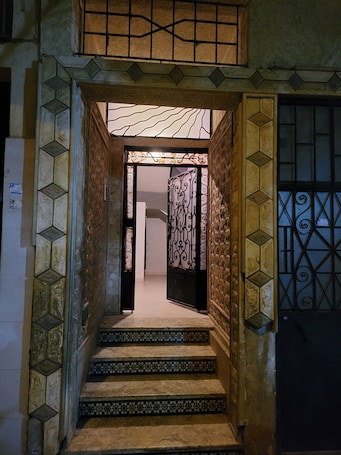 A staircase leading to a room with a patterned wall and a decorative metal gate.