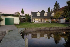 A house with a garage, a front yard, and a small pond. - Okawa Bay Waterfront | Lakefront with Jetty (Rotorua)