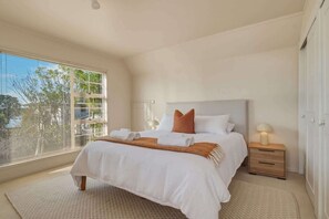A bedroom with a bed, bedside table, lamp, and a window with blinds. - Okawa Bay Waterfront | Lakefront with Jetty (Rotorua)