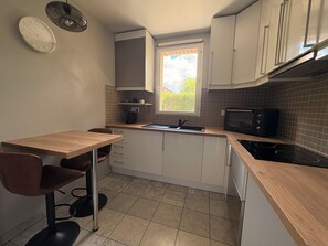 Une cuisine de taille réduite avec une table en bois, un four à micro-ondes et un évier.