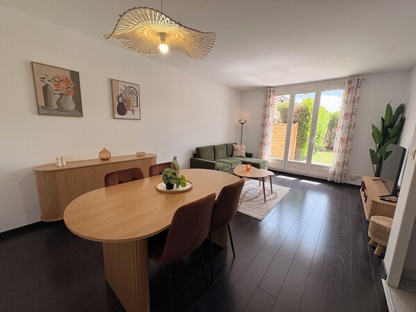 Un salon moderne comprenant un coin repas, un canapé et une grande fenêtre avec des rideaux.