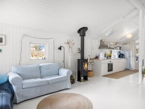 Ein modernes Wohnzimmer mit Sofa, Kamin und Küchenbereich.