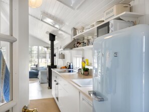 Eine moderne Küche mit weißen Schränken, einem Edelstahlkühlschrank und einem sichtbaren Brotschrank.