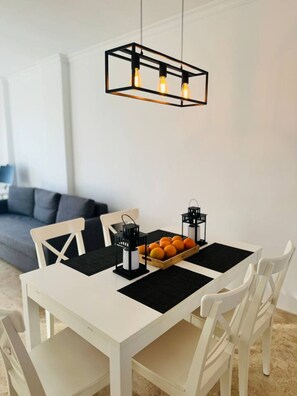 A dining table with white chairs, black placemats, and a black pendant light fixture. - Casa Heidi - Pool, Garage & Terrace - Puerto de Santiago (Santiago del Teide)