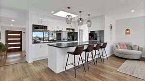 Una cocina moderna con una isla central, taburetes de bar e iluminación colgante.