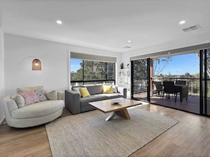 Un salon moderne avec un canapé, une table basse et une vue sur une terrasse extérieure.