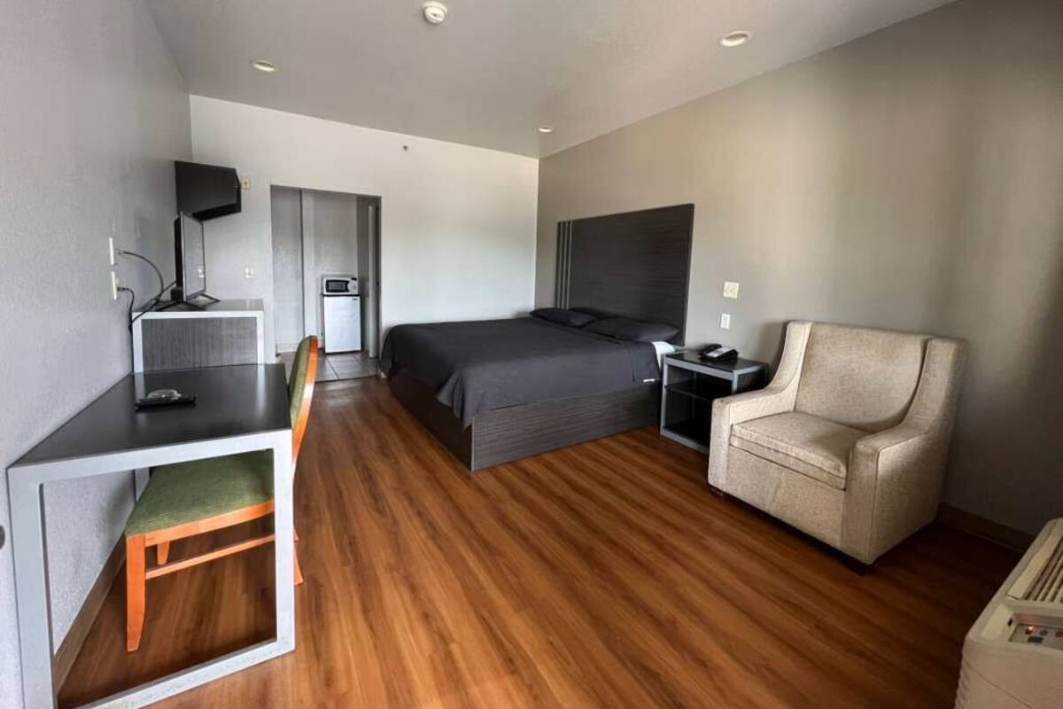 A modern hotel room with a bed, a desk with a chair, a sofa, and a TV.