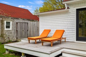 A deck with two wooden lounge chairs and a white exterior wall. - Large Historic Home less than 1 mile from Mansion Beach (New Shoreham)