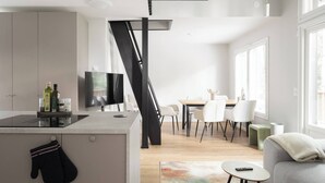 Una cocina moderna con comedor, una escalera y una sala de estar con sofá y mesa de centro.